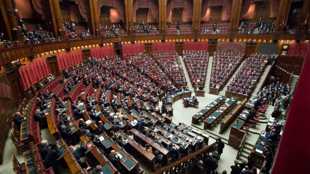 Vue plongeante d'une salle de conseil municipal avec des sièges en velours rouge.