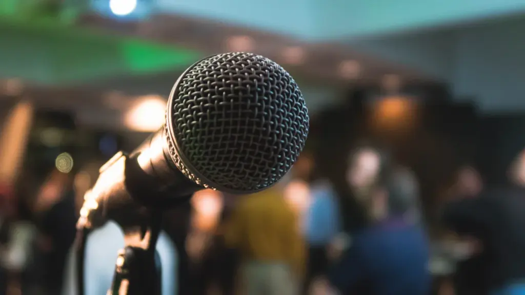 Un microphone sur pied dans une salle de réunion floue pour un débat public.