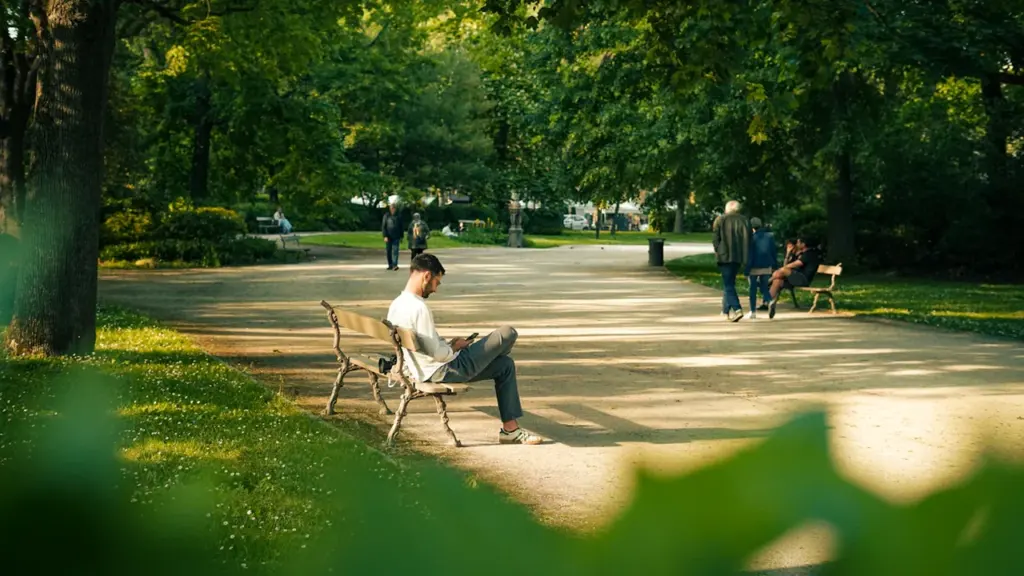 Une personne seule assise sur un banc dans un parc public à Toulouse.