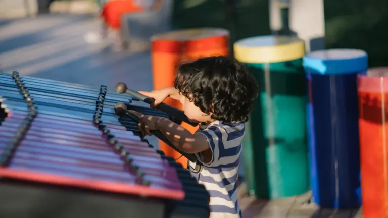 Un jeune garçon joue joyeusement d'un xylophone coloré en extérieur.