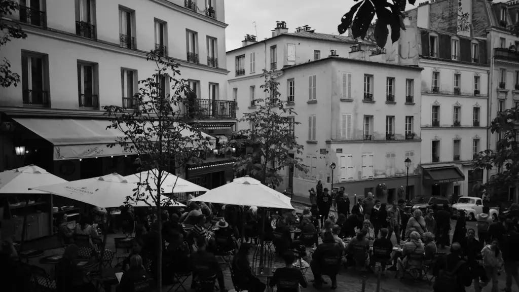 Ambiance conviviale en terrasse à Paris avec des tables sous des parasols blancs.