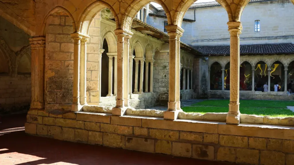 Galerie en pierre d'une ancienne abbaye offrant une vue sur un jardin intérieur.