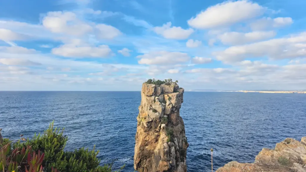 Un impressionnant rocher au milieu de l'océan sous un ciel bleu dégagé.