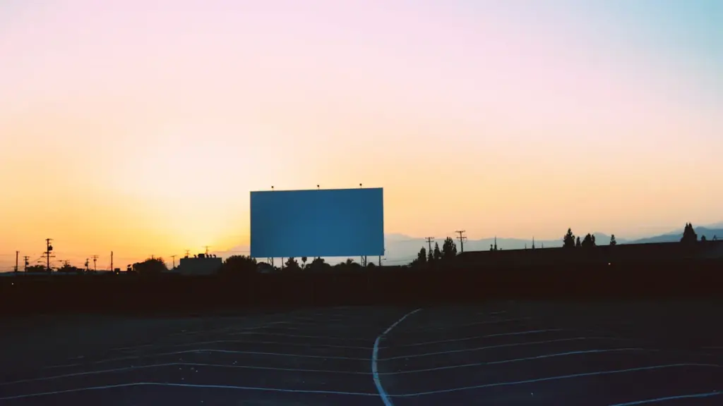 Grand écran de cinéma en extérieur sous un ciel au coucher du soleil.