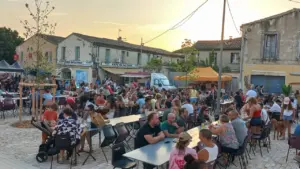Une grande foule de personnes dîne sur des tables en terrasse devant un café.