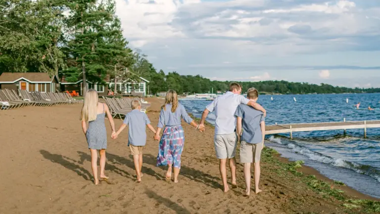 Une famille marchant main dans la main sur une plage ensoleillée en été.