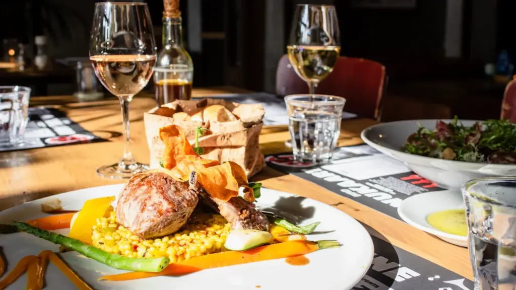 Un plat gastronomique raffiné accompagné de vin sur une table de restaurant.