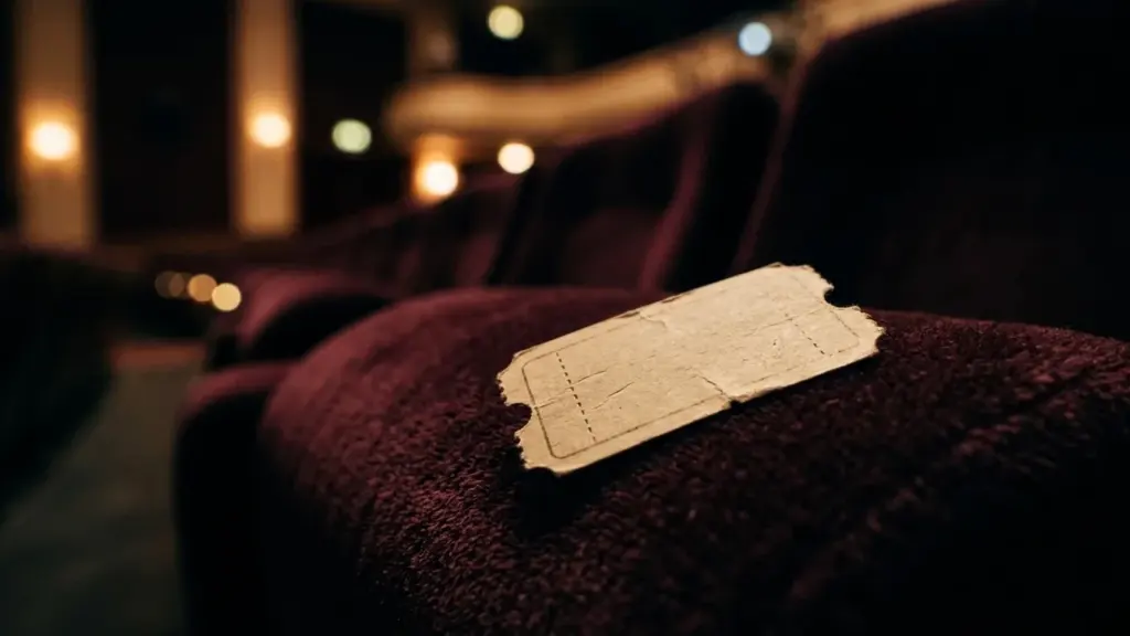 Un billet de cinéma ancien posé sur un siège en velours dans une salle.