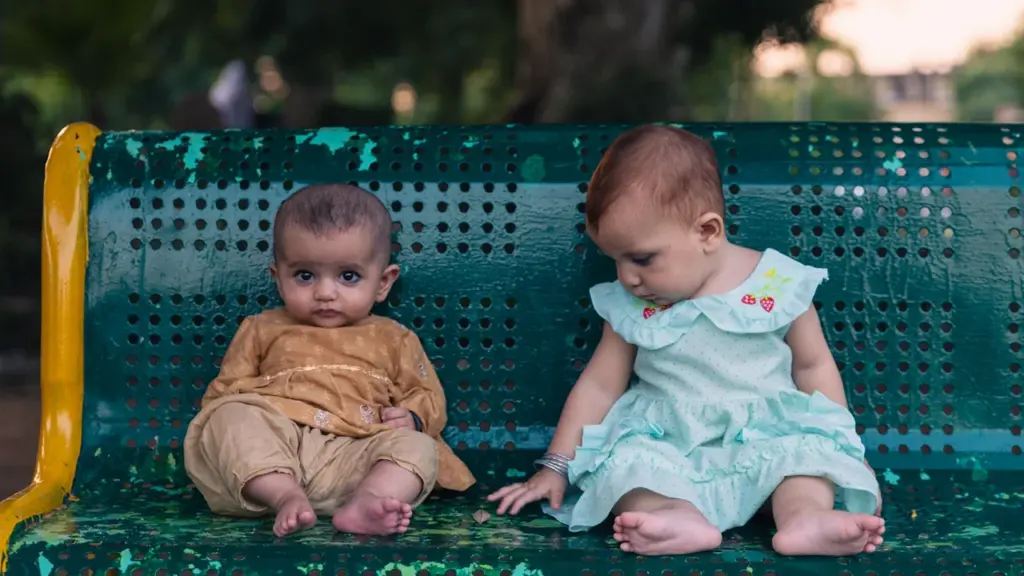 Deux jeunes enfants assis ensemble sur un banc de parc extérieur en été.