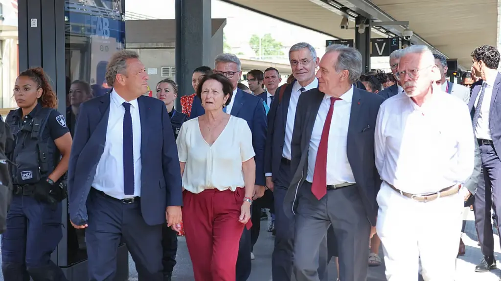 Un groupe de personnalités politiques marche sur un quai de gare sous escorte.