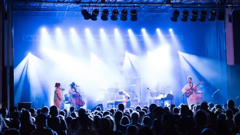 Un groupe de musique jouant sur scène devant un large public en soirée.