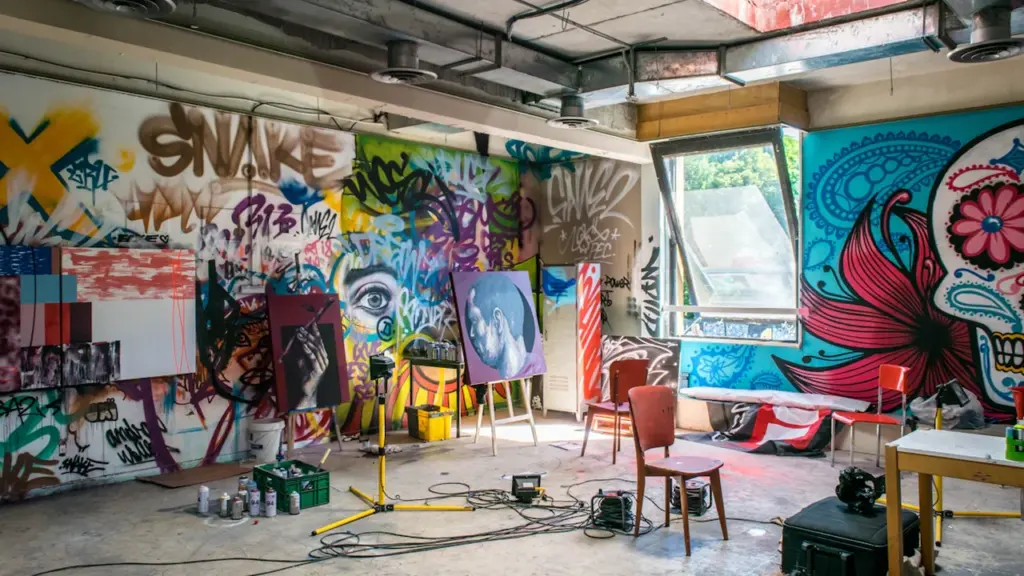 Atelier artistique coloré avec murs recouverts de graffitis et matériel de peinture professionnel.