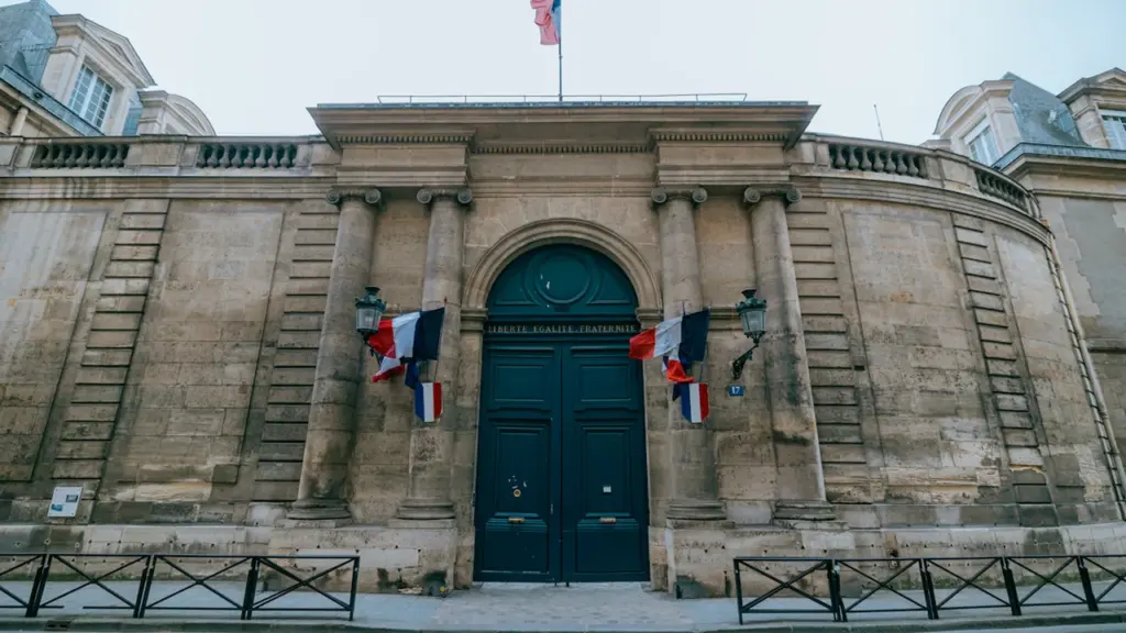 Façade de la mairie de Bordeaux avec des drapeaux français flottant au vent.