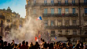 Foule célébrant avec des drapeaux français devant des bâtiments historiques à Bourgoin-Jallieu.