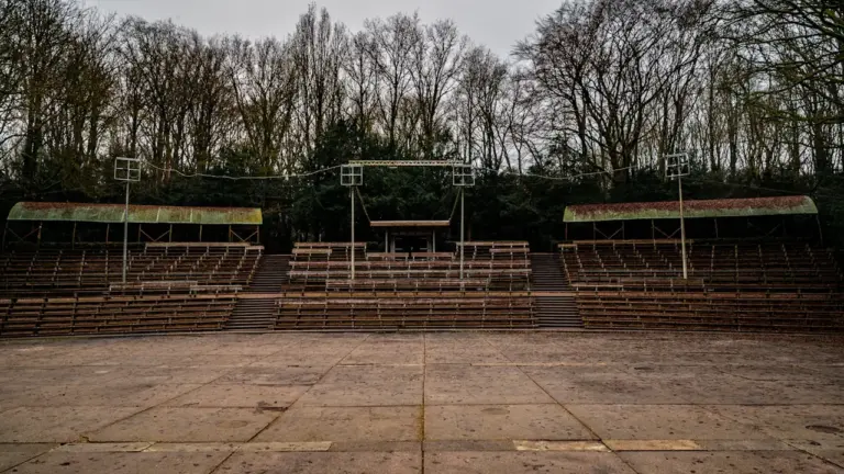 Scène de théâtre en plein air avec des rangées de sièges en bois.