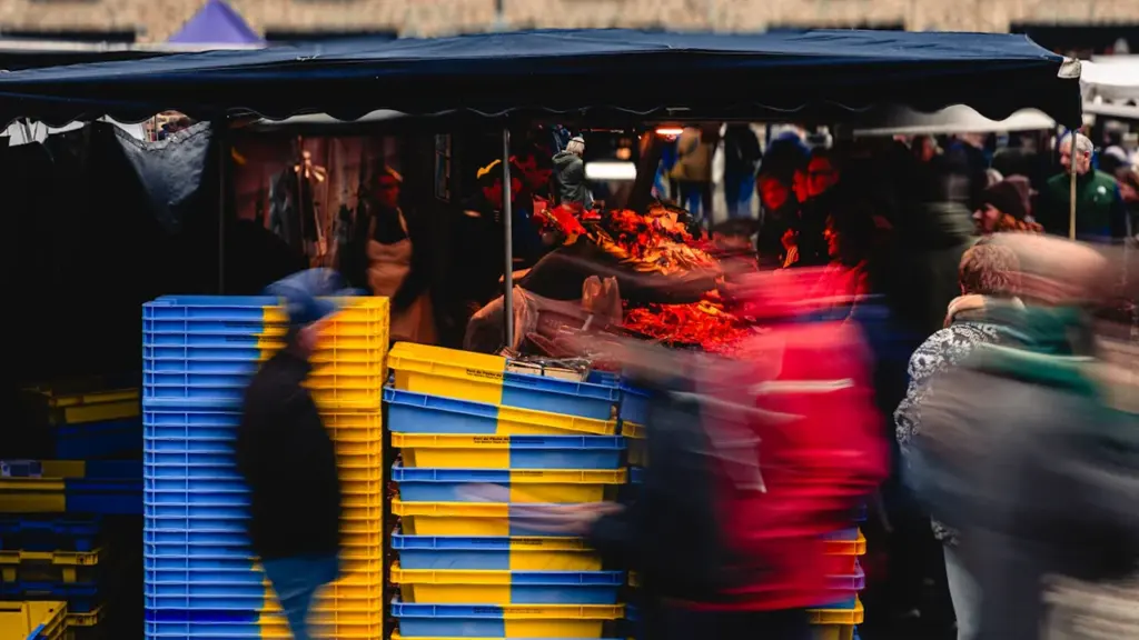 Ambiance animée sur un marché rennais avec des étals colorés et des passants flous.