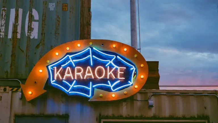 Enseigne néon lumineuse affichant le mot Karaoke sur un conteneur industriel urbain.