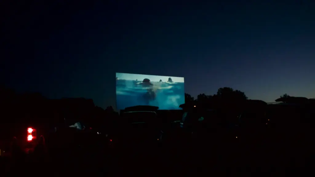 Un grand écran de cinéma en plein air sous un ciel nocturne étoilé.