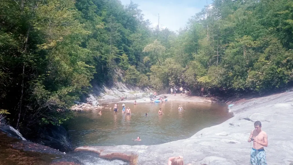 Baigneurs profitant d'un bassin naturel entouré d'arbres pour se rafraîchir lors d'une canicule.