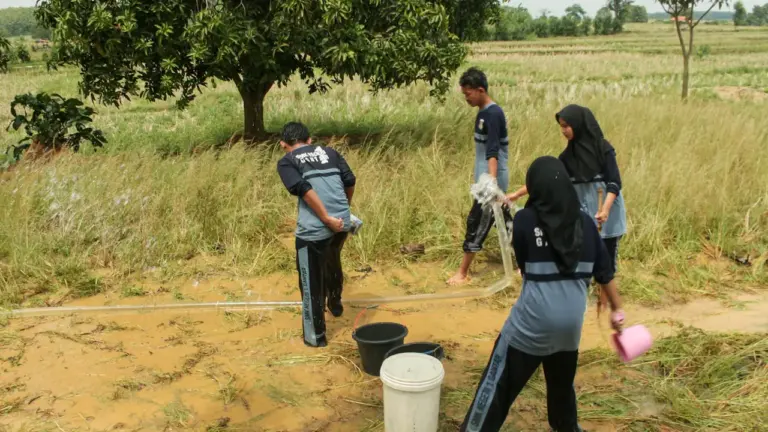 Des écoliers collectant de l'eau dans un environnement rural pour un projet scolaire.