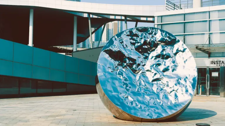 Une sculpture sphérique moderne en métal réfléchissant sur une place urbaine à Agen.