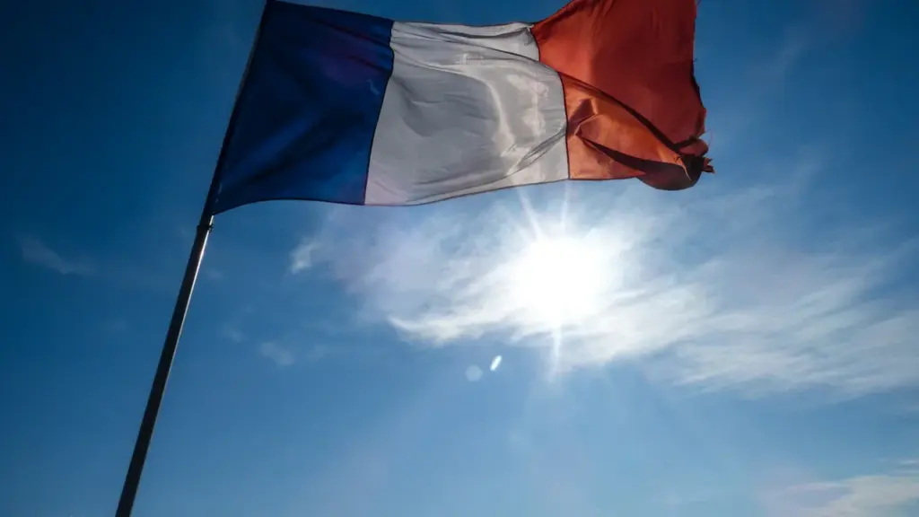 Un drapeau français flottant sous un ciel bleu ensoleillé et lumineux.