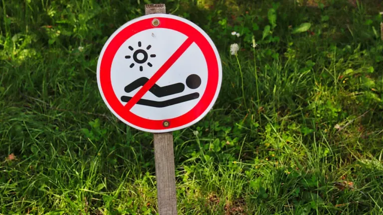 Panneau interdisant le bronzage sur fond de champ d'herbe verte