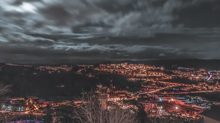 Vue aérienne nocturne des lumières de la ville de Saint-Étienne sous un ciel nuageux.