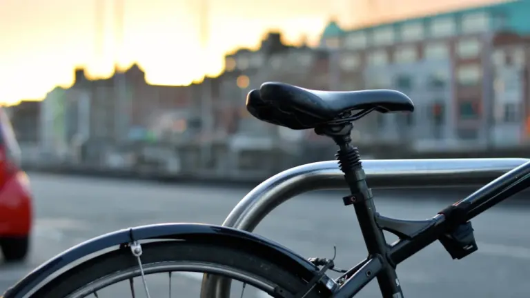 Gros plan sur une selle de vélo garée en ville au coucher du soleil.
