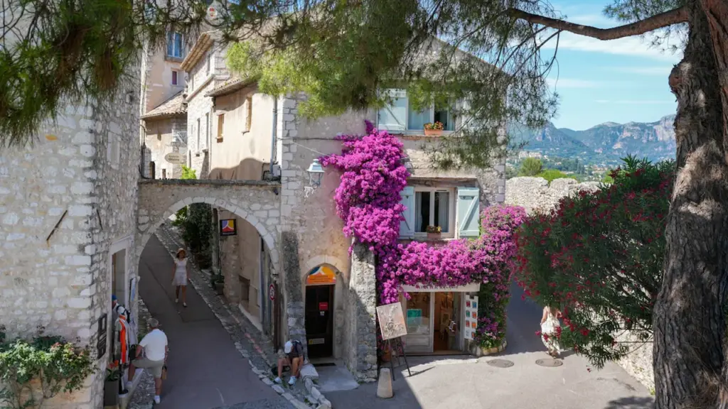 Vue pittoresque d'une ruelle de village français ornée de fleurs violettes en été.