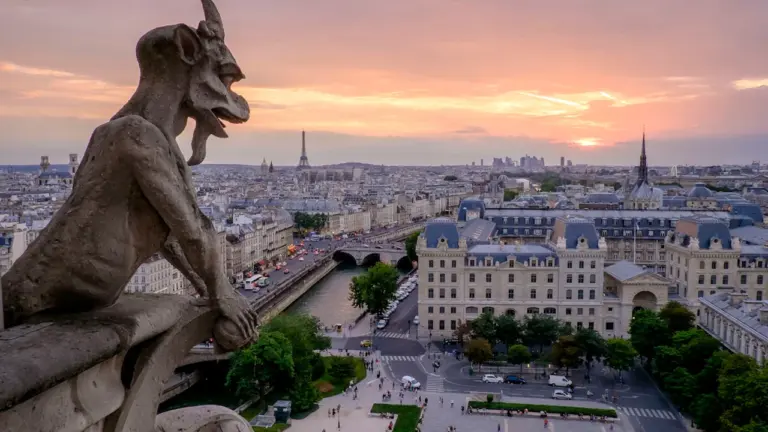 Gargouille de Notre-Dame surplombant le paysage urbain parisien au lever du soleil.