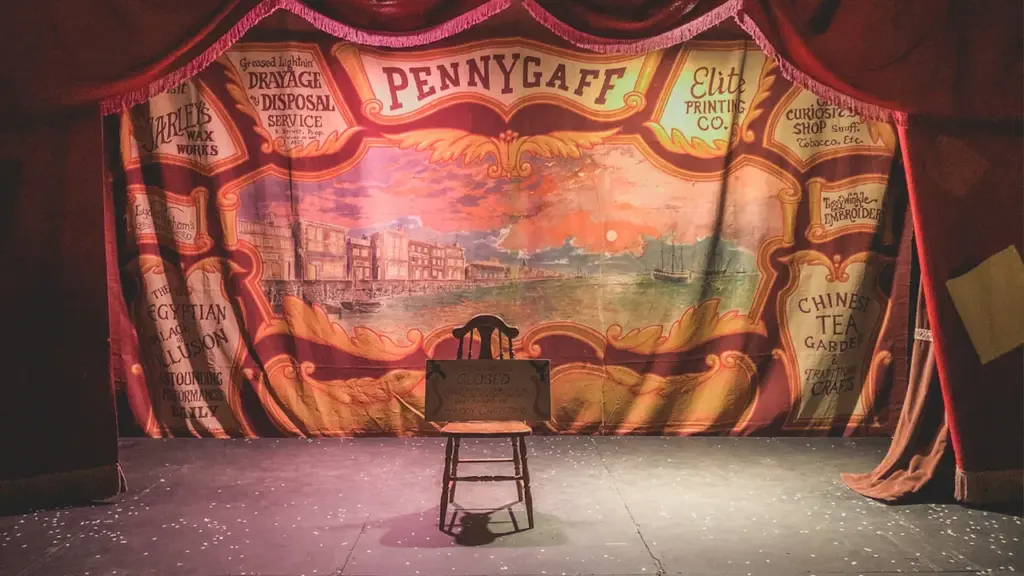 Une scène de théâtre vide avec un décor ancien et une chaise solitaire.