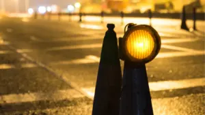 Deux cônes de signalisation avec une lampe clignotante orange sur une route nocturne.