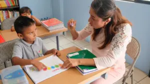 Une enseignante travaillant avec un jeune élève dans une salle de classe scolaire.