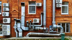 Façade en briques d'un bâtiment équipée de nombreuses conduites de ventilation industrielle.