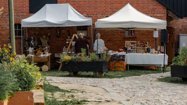 Tentes blanches installées devant un bâtiment en briques pour un marché associatif local.