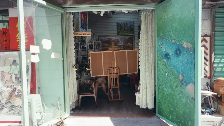 Portes vertes ouvertes sur un atelier d'artiste avec un chevalet en bois.