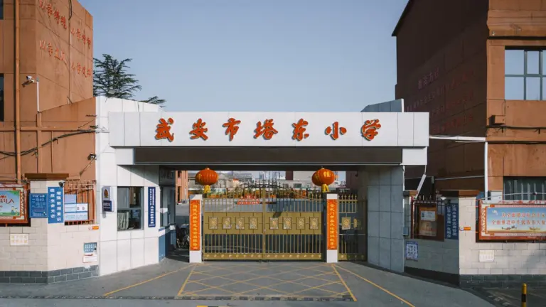 Portail d'entrée d'une école avec des grilles dorées et des lanternes décoratives.