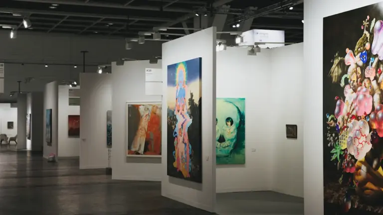 Galerie d'art contemporain lumineuse exposant plusieurs peintures sur des murs blancs élégants.