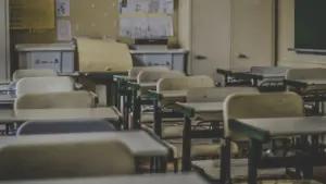 Une salle de classe vide avec des pupitres et des cahiers en désordre.