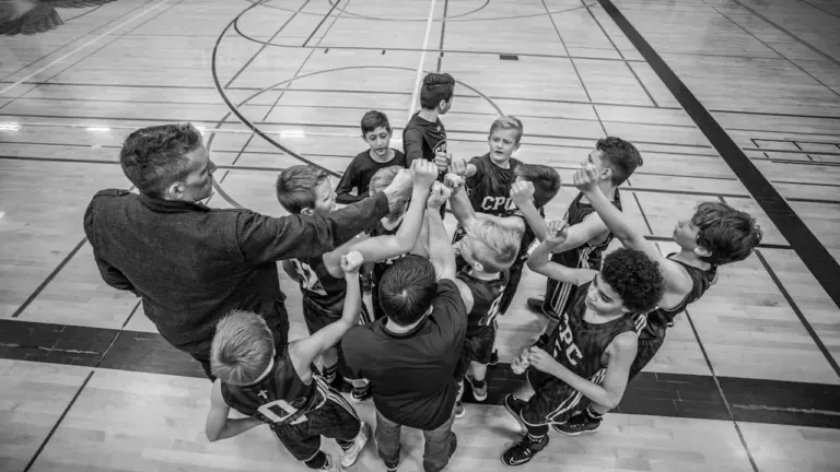 Une équipe de jeunes sportifs en cercle, mains réunies, illustrant la cohésion et l'effort.