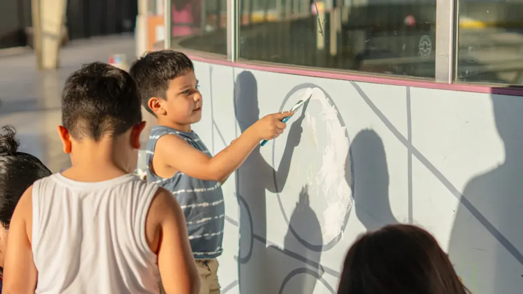 Des enfants participent à un atelier de peinture créatif sur un mur blanc.