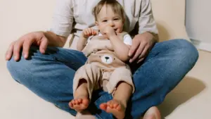 Un bébé assis sur les genoux de son parent, évoquant la petite enfance.