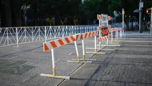 Barrières de sécurité orange et blanches bloquant une rue lors d'un événement urbain.
