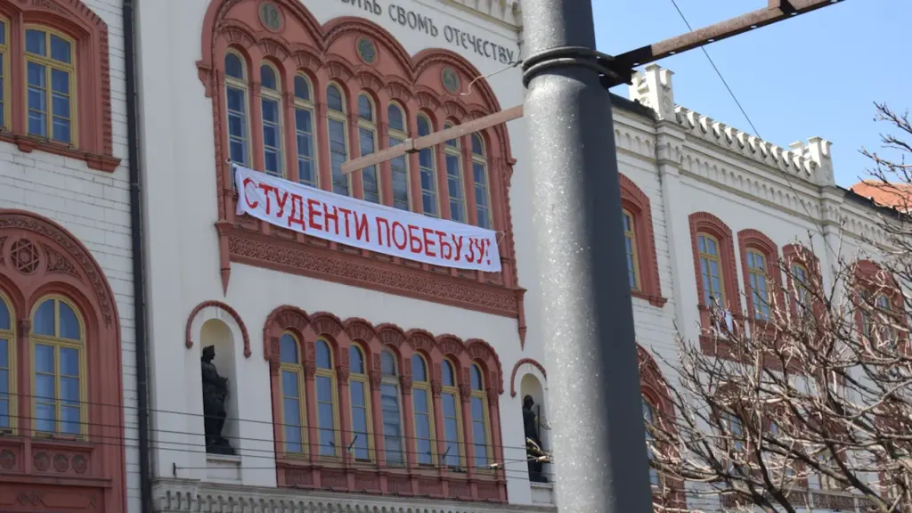 Banderole de protestation étudiante accrochée sur la façade d'un bâtiment institutionnel historique.