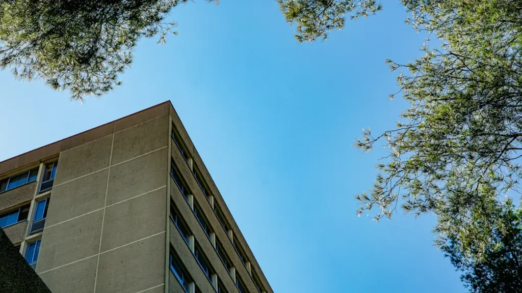 Vue en contre-plongée d'un bâtiment universitaire moderne sous un ciel bleu dégagé.