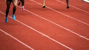 Plusieurs athlètes en pleine course sur une piste d'athlétisme professionnelle en extérieur.